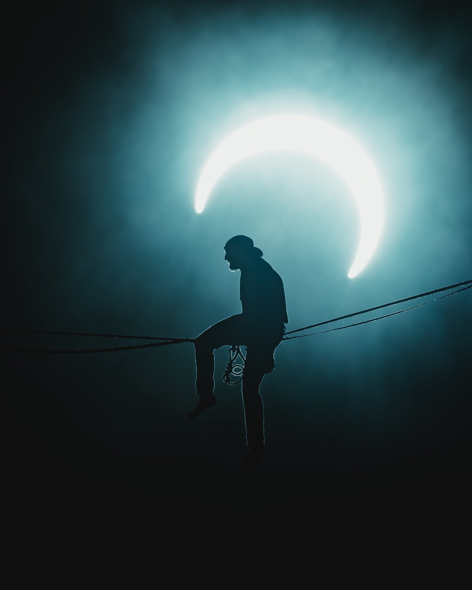 Ryan Robinson sitting on a highline silhouetted by the moon